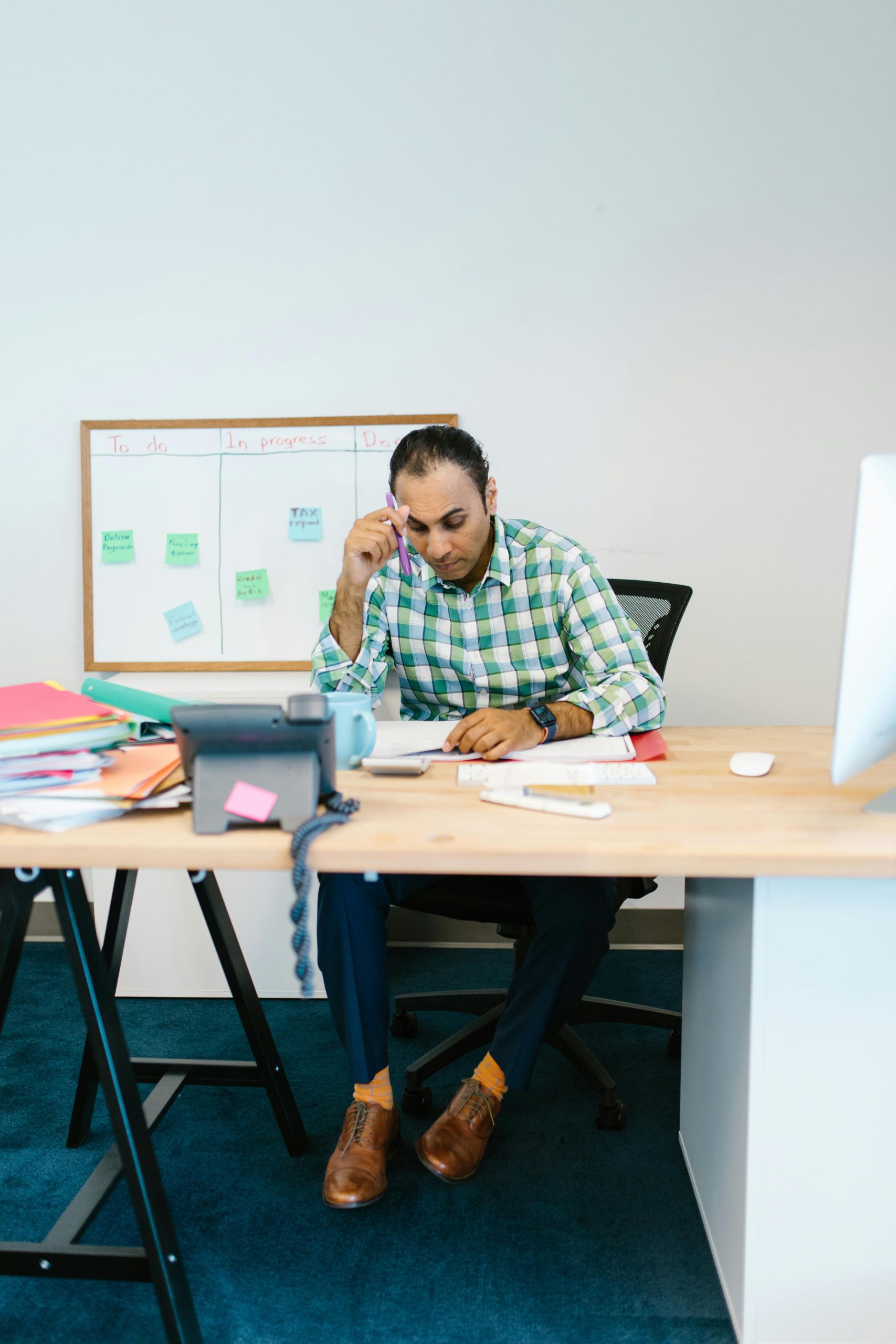 A focused man working at his desk with papers, showcasing a thoughtful work environment.